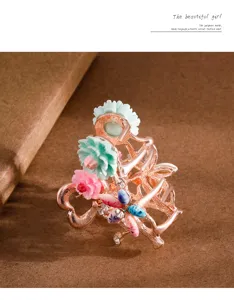 Close-up detail of rose gold hair claw clip featuring enamel mint pink flowers and small crystal.