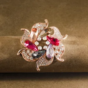 Close-up detail of a rose gold flower brooch featuring sparkling rhinestones and colorful crystals.