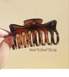 Close-up detail shot of the brown resin hair claw clip, showing its hollow teeth and texture.