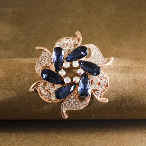 Elegant flower brooch detail featuring rose gold metal and sparkling blue and clear crystals.
