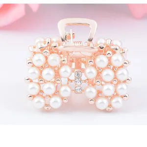 Élégante pince à cheveux dorée rose décorée de perles blanches et de strass brillants.