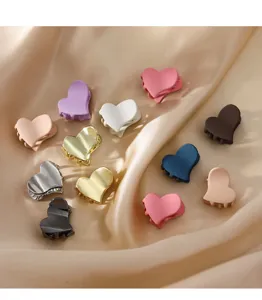 Vista detallada de mini pinzas para el cabello con forma de corazón en acabados metálicos y mate.