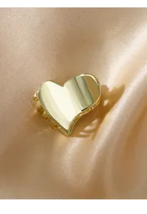 Vista detallada de la pinza para cabello en forma de corazón dorado sobre fondo satinado.