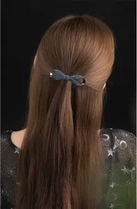 Detail shot of a sparkling blue crystal bow hair clip, elegant hair accessory for ponytail.