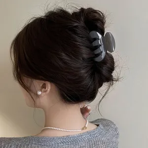 Detail shot of grey hair claw clip, elegant small pumpkin design for stylish hair buns.
