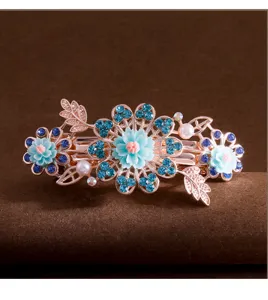 Detailed close-up of a crystal flower hair clip with blue rhinestones and rose gold tone.