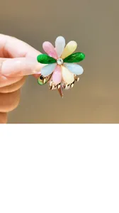 Colorful floral hair claw clip detail shot showing resin petals and crystal rhinestone.
