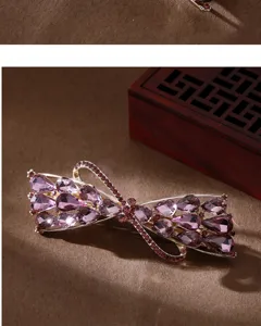 Detailed shot of sparkling purple rhinestone bow hair clip, elegant metal barrette for women.