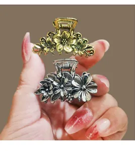 Detailed close-up of vintage metallic floral hair claws in gold and silver, perfect for styling.