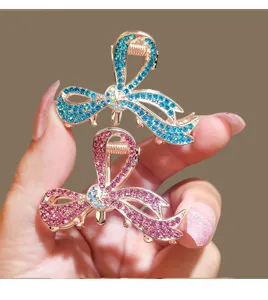 Detailed close-up of shiny rhinestone bow hair claw clips, elegant metal styling accessory.