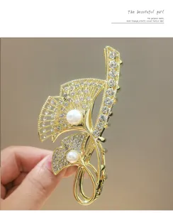 Detail shot of a golden ginkgo leaf hair claw clip featuring sparkling rhinestones and pearls.