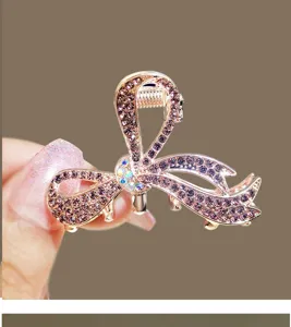 Closeup of sparkling rhinestone bow hair claw clip, elegant purple crystal detail design.