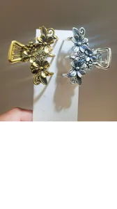 Small metal hair claw clips with elegant flower design, silver and gold finish for styling.