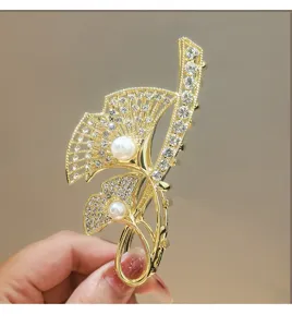 Close-up detail of luxury fan-shaped rhinestone hair claw clip with faux pearls for women.