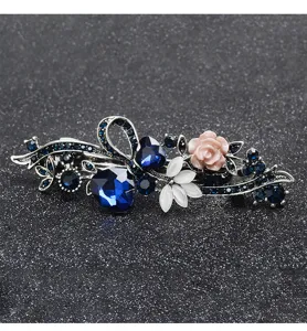 Detailed view of vintage rhinestone spring hair clip with blue gems and pink rose.