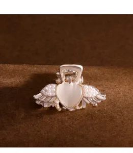 Petite pince à cheveux dorée avec opale cœur et ailes d'ange en perles pour coiffures élégantes.