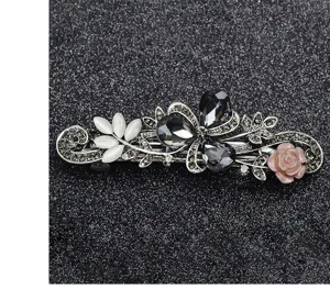 Detail view of a vintage rhinestone spring hair clip with floral crystal and pink rose accents.