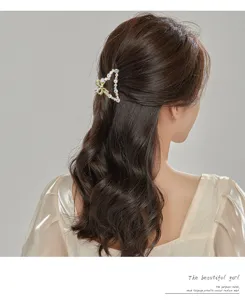 Detail view of elegant triangle metal hair claw clip decorated with pearls and sparkly rhinestones.