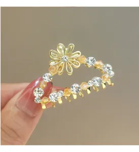 Close-up detail of golden metal rhinestone hair claw clip with crystal flowers for elegant hair.