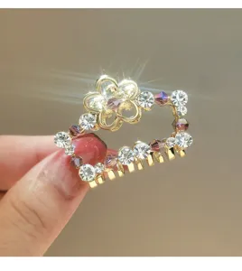 Close up of gold metal hair claw clip detailed with sparkling rhinestones and purple crystals.