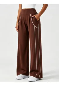 Detail view of women's brown high-waisted wide-leg athletic pants with white piping trim.