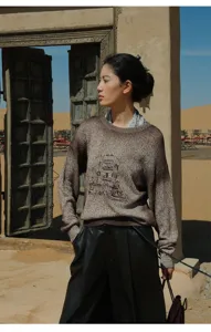 Detailed view of the brown gradient knit crewneck sweater featuring an artistic building graphic.