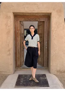 Detailed view of contrast striped short sleeve knit top and wide shorts in antique street scene.