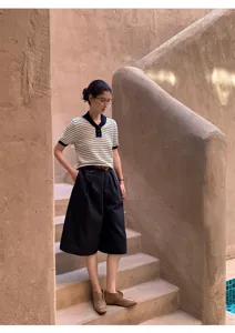 Detailed view of a chic color-block striped short-sleeve knit top in an architectural scene.