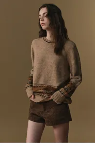 Detailed view of a stylish women's knit sweater and brown shorts set with retro patterns.