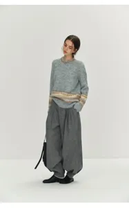Detailed view of women's grey knit sweater and high-waisted pleated harem pants outfit.