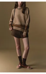 Detailed view of women's high-waisted wool blend shorts styled with a patterned sweater and sandals.