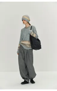 Details of grey high-waist pleated harem pants, woolen knit sweater and matching knit beanie.