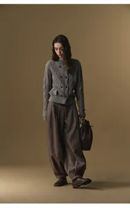 Detail view of the wool blend pleated harem trousers paired with a classic cable knit cardigan.