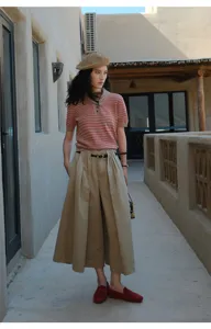 Outdoor fashion detail shot showing striped knit polo shirt and khaki wide-leg pants.
