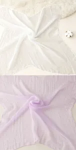 Detail van fijne gaassjaal met zachte textuur en lichte zomerse kleuren voor dames.