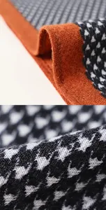 Vue rapprochée détaillée de la texture du tissu de l'écharpe et de sa bordure orange.