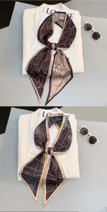 Close-up detail of a chic narrow silk scarf with modern geometric lines, styled flat.