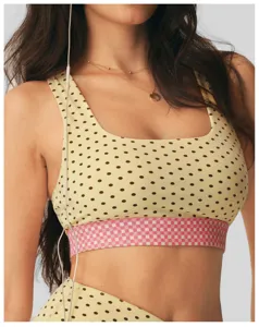 Detail van sportbeha met stipjes en vierkante hals en roze geruite elastische band en pasvorm.