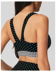Gedetailleerd rugaanzicht van de zwart-witte polkadot sportbeha met geruite onderband.