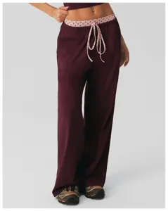 Gedetailleerd overzicht van losse loungebroek met hoge taille, roze stipjesband en trekkoorden.