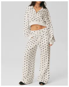 Gedetailleerd overzicht van witte polkadot crop top met halve rits en wijde broek.