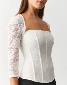 Detail view of a white lace square neck long sleeve corset top, showing intricate floral lace.