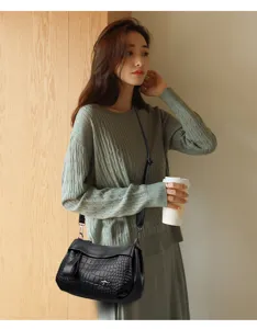 Detailed view of the stylish black faux leather crossbody bag worn by model in lifestyle setting.