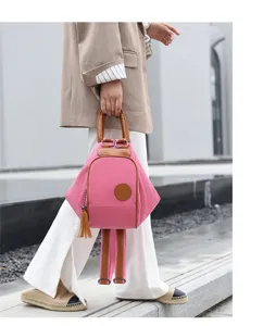 Close up of pink canvas backpack detail with brown leather handles and chic tassel charm.