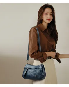 Detailed view of blue crocodile pattern leather shoulder bag with chic metal kangaroo logo accent.