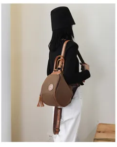 Detail view of the brown canvas women backpack featuring leather handles and chic tassel design.