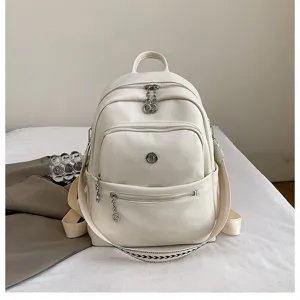 Detailed view of a stylish white leather backpack featuring multiple zipped pockets and straps.