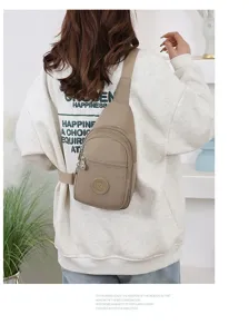 Detailed shot of casual nylon sling chest bag in light khaki, featuring zipper pockets.