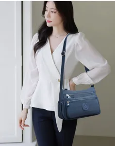 Stylish blue nylon crossbody bag for women, featuring multiple zipper pockets and strap.