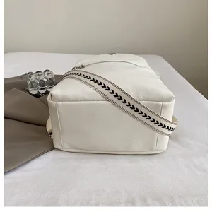 Close-up detail of a women's white casual leather backpack featuring a patterned woven strap.